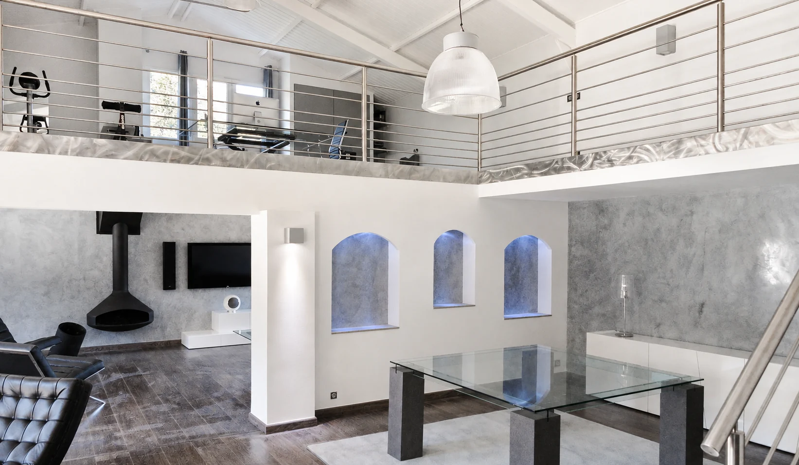 Cloison avec trois niches éclairées sous une mezzanine dans un séjour.