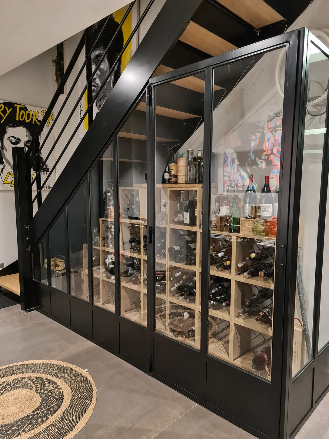 Salon rénové avec finitions murales grises, cheminée suspendue et mobilier noir.