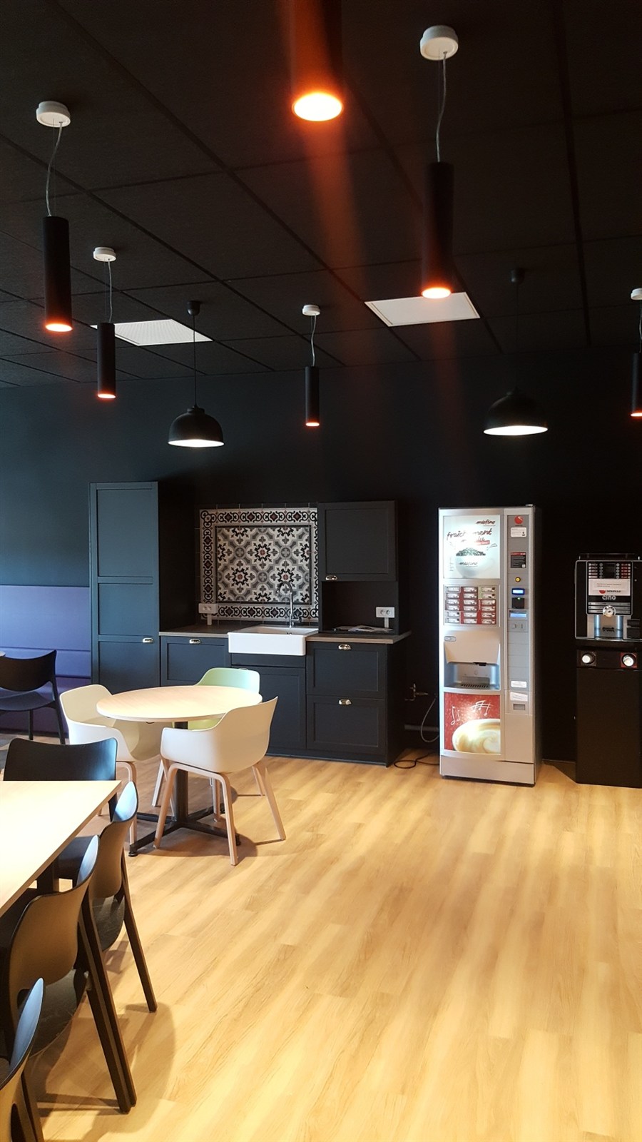 Salle à manger avec plafond à éclairage indirect, lustre et papier peint à motifs dorés.